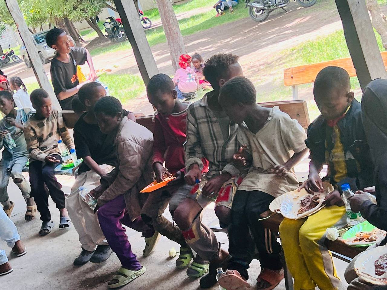 Children eating together under a covered shelter