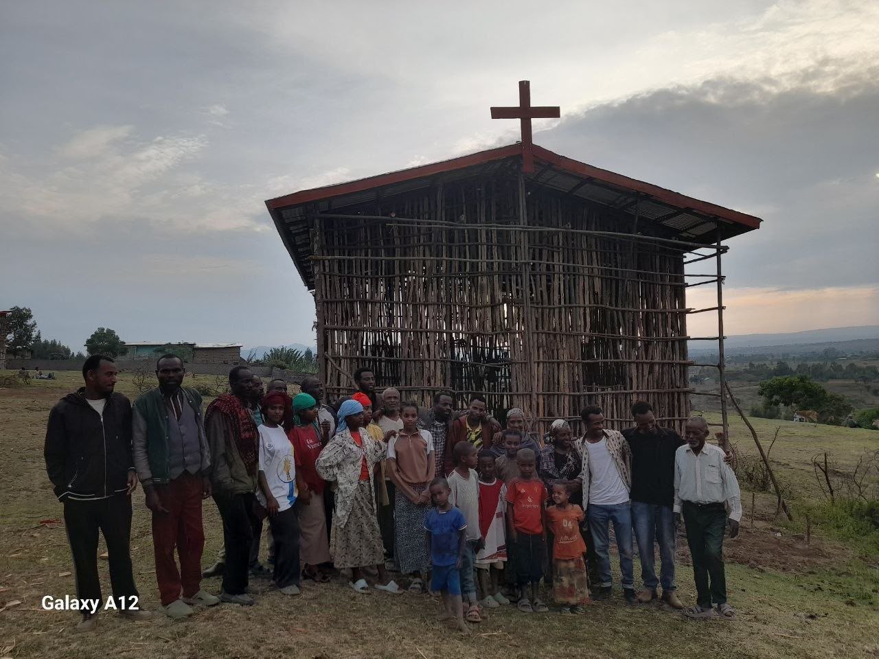 Community members and children gathered in front of the finished church at dusk