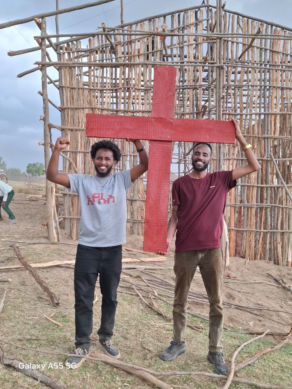 Two men celebrating, holding up the finished wooden cross