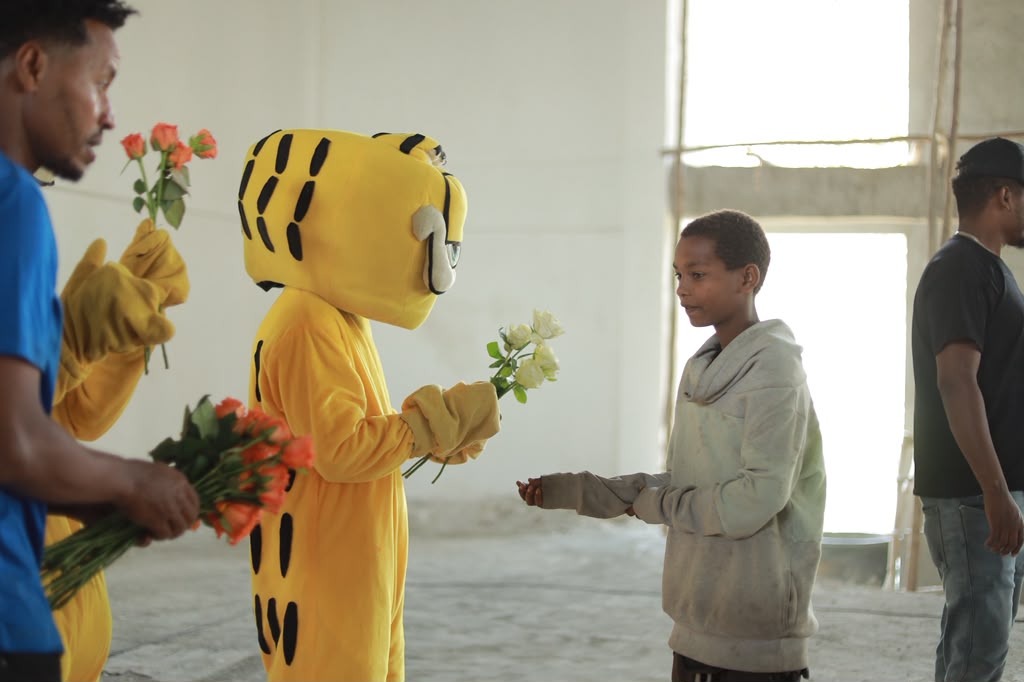 A costumed mascot handing flowers to a boy at an event