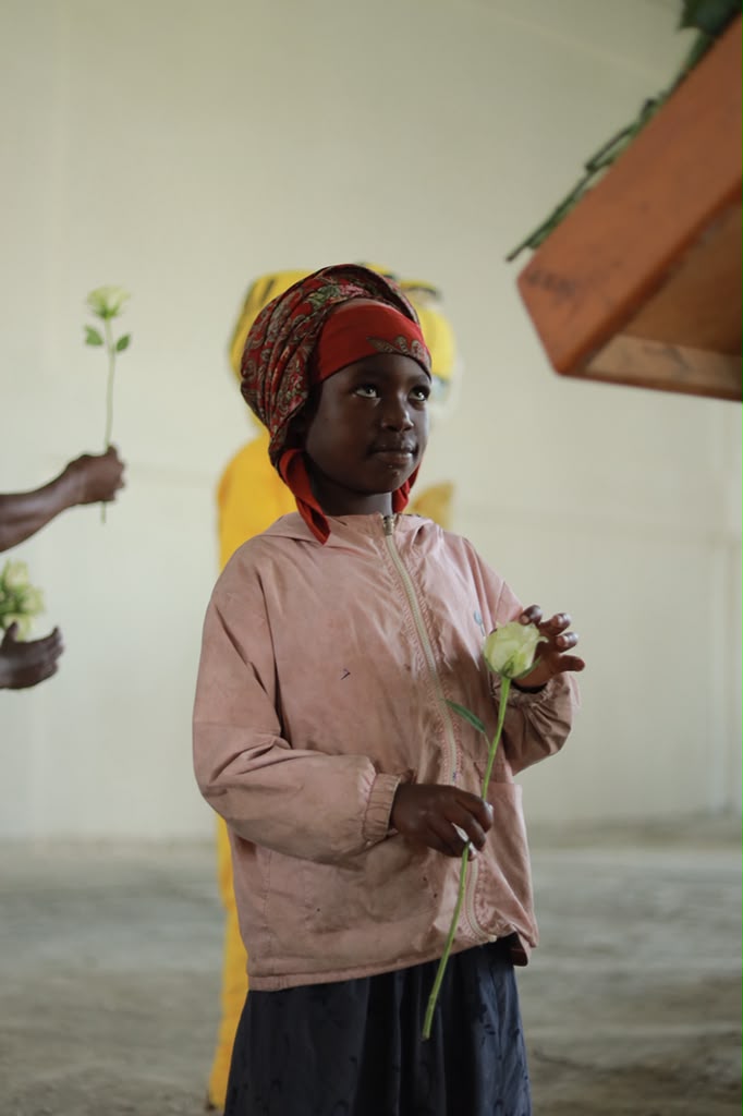 Girl in a headscarf holding a white flower indoors
