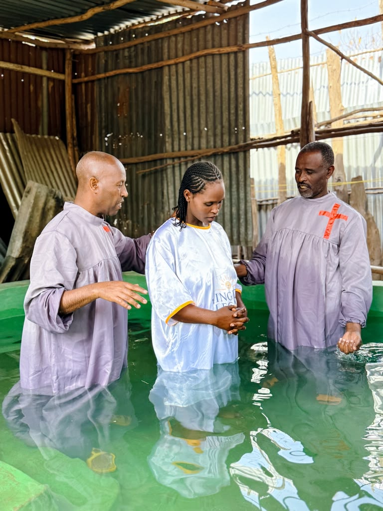 Two ministers baptizing a woman in a water tank
