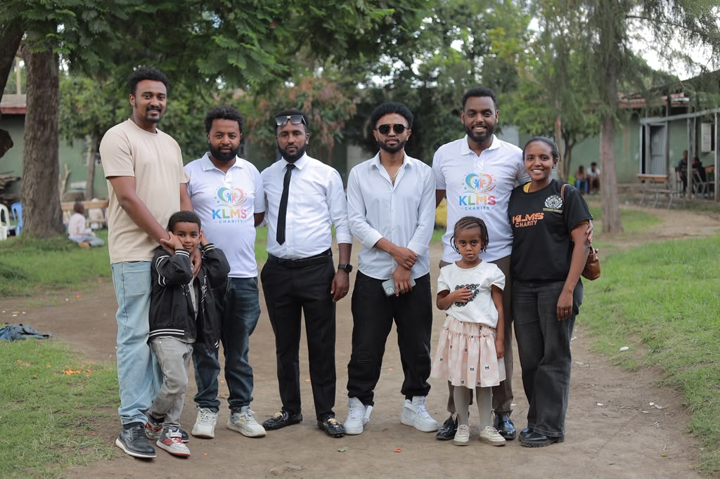 KLMS team members in charity t-shirts posing outdoors with children